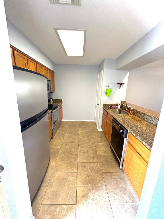 kitchen featuring stainless steel appliances, sink, dark stone counters, and light tile floors