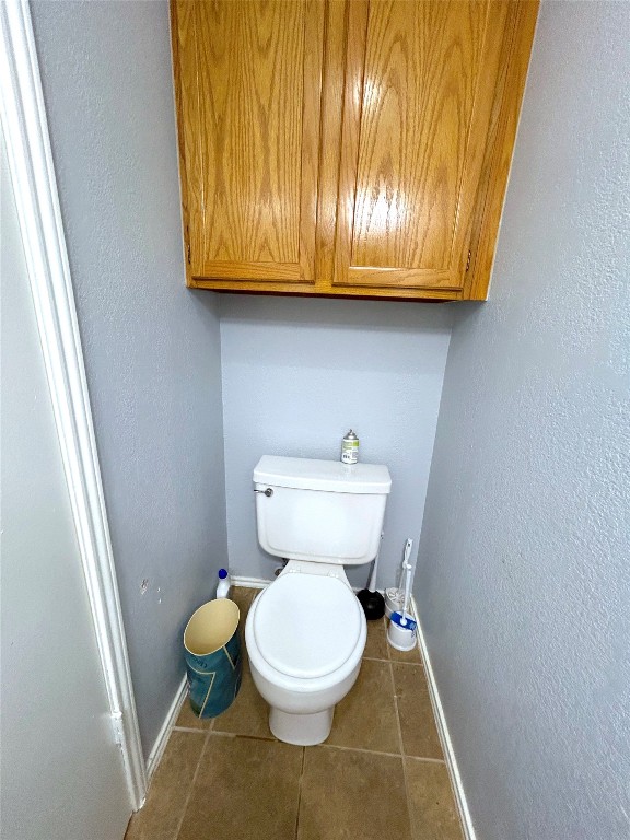 bathroom featuring tile flooring and toilet