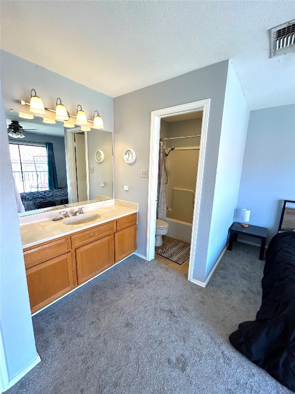 bathroom with a textured ceiling, vanity, toilet, and ceiling fan