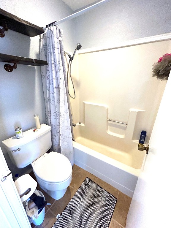 bathroom with tile floors, toilet, and shower / bath combo with shower curtain