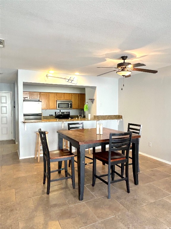 tiled dining space with ceiling fan and a textured ceiling