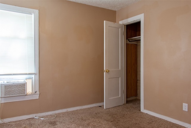 unfurnished bedroom featuring a closet, a textured ceiling, light colored carpet, and multiple windows