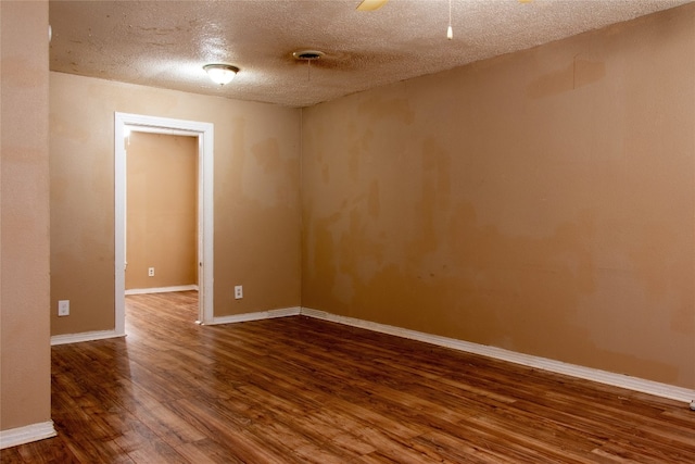 unfurnished room featuring dark wood-type flooring and a textured ceiling