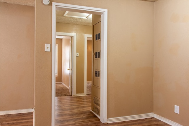 hallway with dark wood-type flooring and a textured ceiling