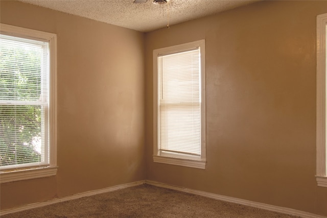 unfurnished room featuring dark colored carpet and a textured ceiling