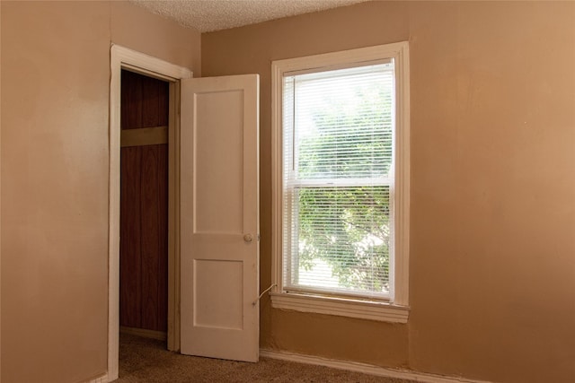 unfurnished bedroom featuring a closet, dark carpet, and multiple windows