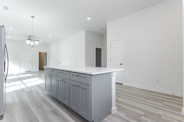 kitchen with stainless steel refrigerator, ceiling fan, gray cabinetry, a center island, and light wood-type flooring