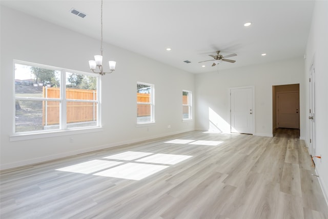 unfurnished living room with ceiling fan with notable chandelier and light hardwood / wood-style floors