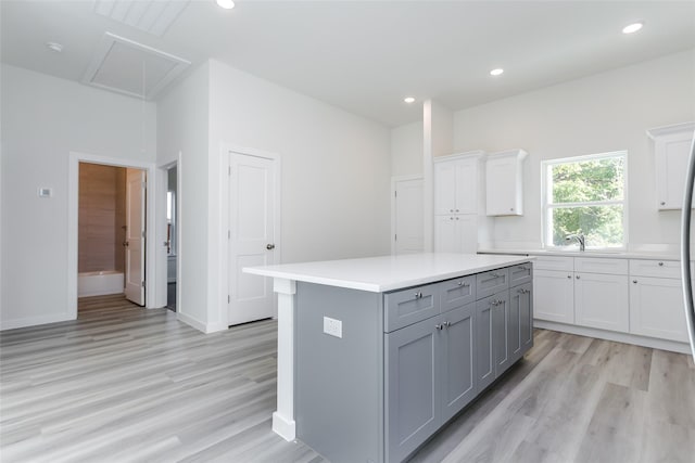 kitchen with sink, gray cabinets, white cabinetry, a center island, and light hardwood / wood-style floors