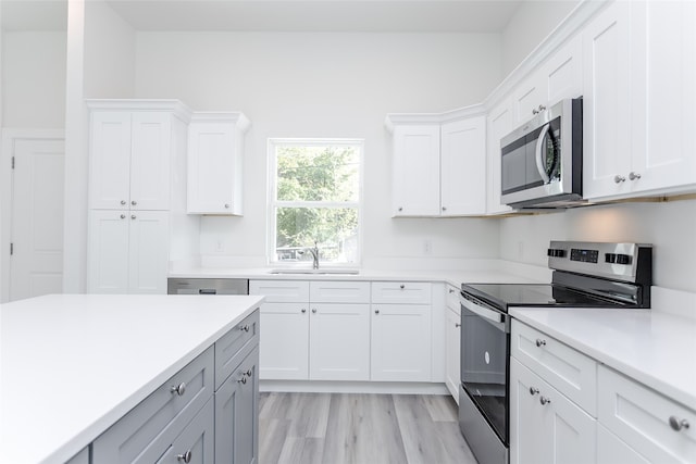 kitchen featuring stainless steel appliances, white cabinetry, sink, and light wood-type flooring