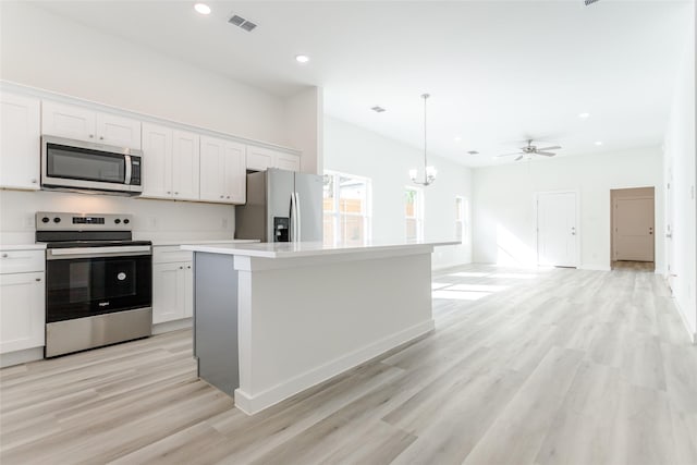 kitchen featuring stainless steel appliances, white cabinetry, hanging light fixtures, and a center island