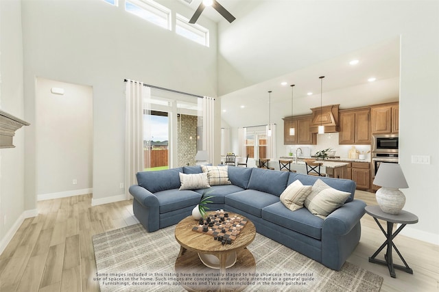 living room with a high ceiling, light hardwood / wood-style floors, and ceiling fan