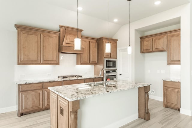 kitchen with appliances with stainless steel finishes, sink, decorative light fixtures, lofted ceiling, and an island with sink