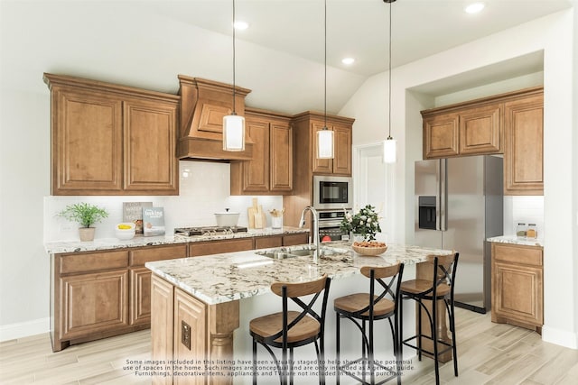 kitchen with sink, hanging light fixtures, vaulted ceiling, a center island with sink, and appliances with stainless steel finishes