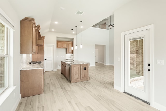 kitchen featuring hanging light fixtures, ceiling fan, light wood-type flooring, light stone countertops, and appliances with stainless steel finishes