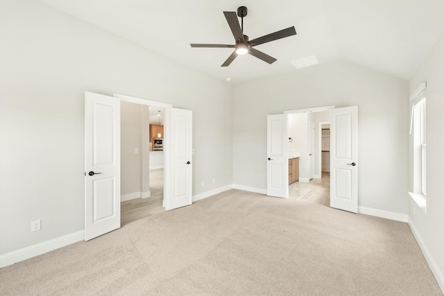 unfurnished bedroom with ceiling fan, ensuite bathroom, light carpet, and lofted ceiling