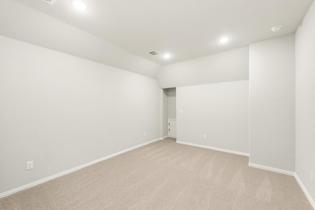 carpeted empty room featuring vaulted ceiling