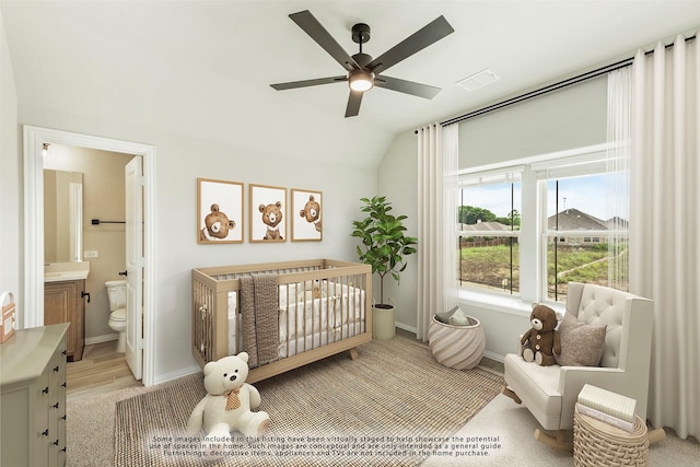 bedroom with ensuite bath, ceiling fan, a nursery area, light hardwood / wood-style floors, and lofted ceiling