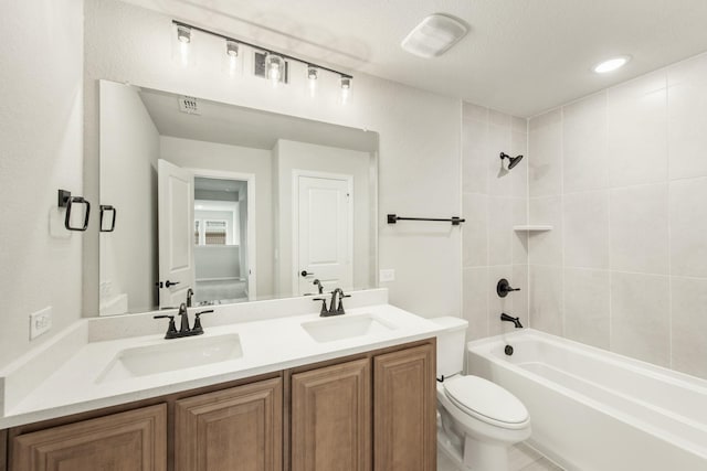 full bathroom featuring vanity, toilet, a textured ceiling, and tiled shower / bath combo