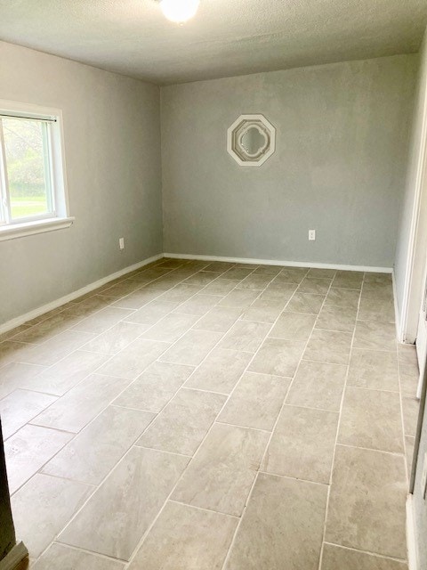 tiled empty room with a textured ceiling