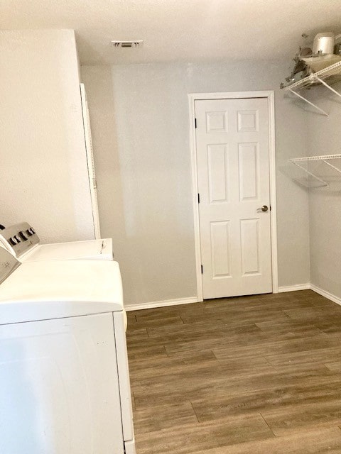 clothes washing area with washing machine and dryer and light wood-type flooring