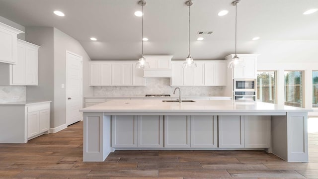 kitchen featuring pendant lighting, white cabinets, sink, appliances with stainless steel finishes, and a large island