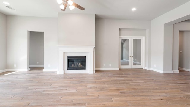 unfurnished living room with french doors, light wood-type flooring, and ceiling fan