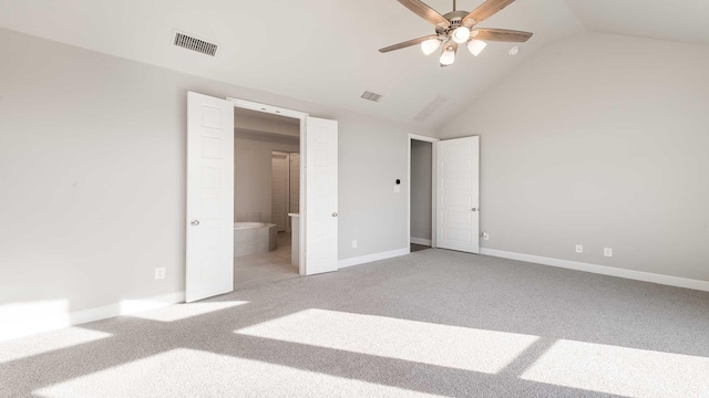 unfurnished bedroom with ceiling fan, light colored carpet, ensuite bathroom, and vaulted ceiling