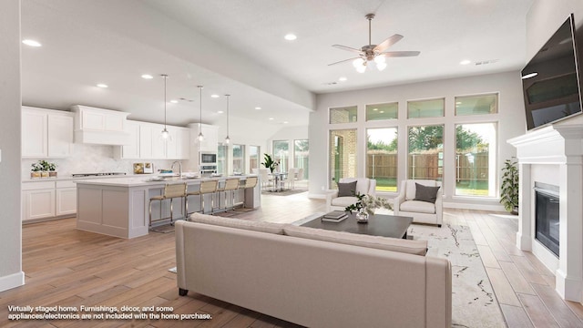 living room featuring ceiling fan, sink, and light hardwood / wood-style flooring