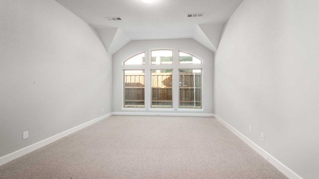 carpeted empty room with lofted ceiling