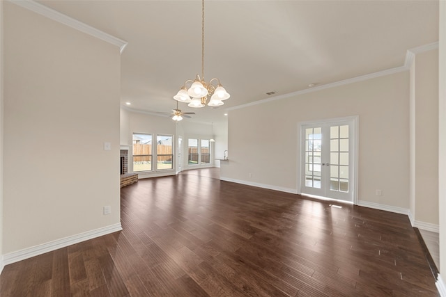 empty room featuring dark wood-type flooring, ornamental molding, ceiling fan with notable chandelier, and plenty of natural light