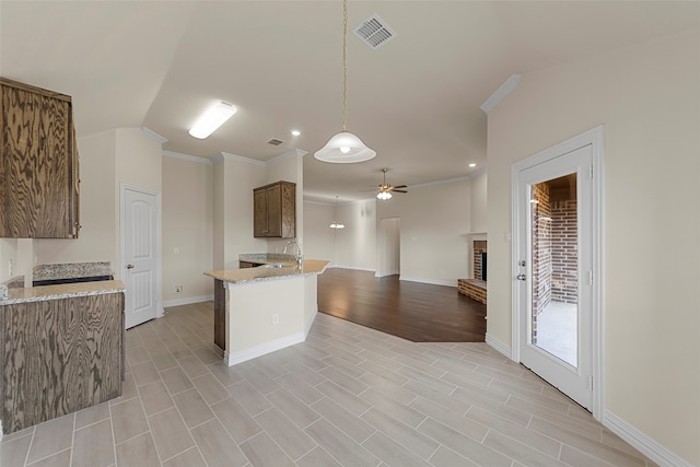 kitchen featuring crown molding, hanging light fixtures, a brick fireplace, ceiling fan, and sink