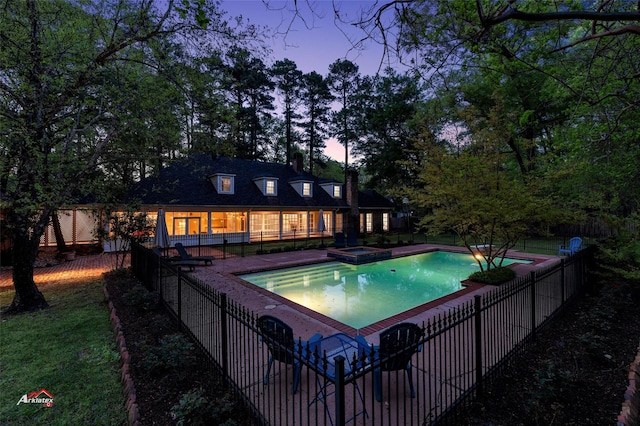 pool at dusk featuring an in ground hot tub