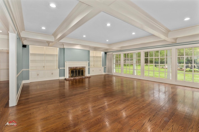 unfurnished living room featuring ornamental molding, hardwood / wood-style flooring, built in features, a brick fireplace, and beam ceiling