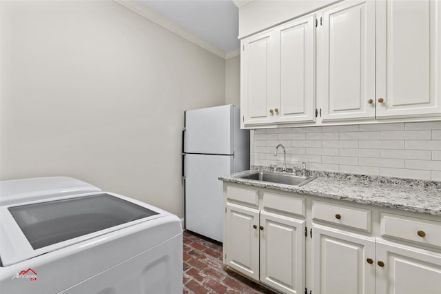 laundry room with washing machine and dryer, ornamental molding, cabinets, and sink