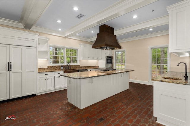 kitchen featuring dark stone countertops, island range hood, a center island, sink, and white cabinetry