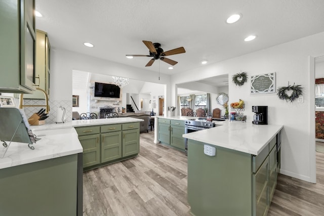 kitchen with light hardwood / wood-style floors, green cabinets, ceiling fan, kitchen peninsula, and tasteful backsplash