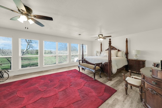 bedroom with ceiling fan, multiple windows, and light hardwood / wood-style flooring