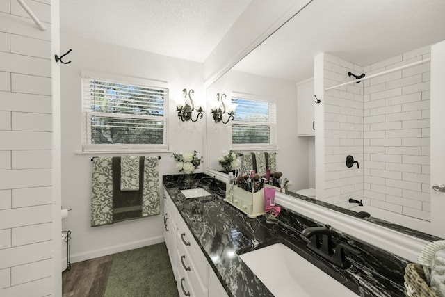 bathroom featuring double vanity, tiled shower / bath combo, and wood-type flooring