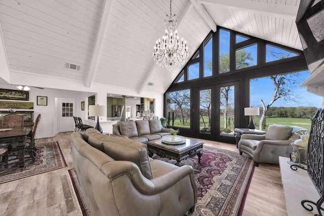 living room featuring a healthy amount of sunlight, a notable chandelier, high vaulted ceiling, light hardwood / wood-style floors, and french doors