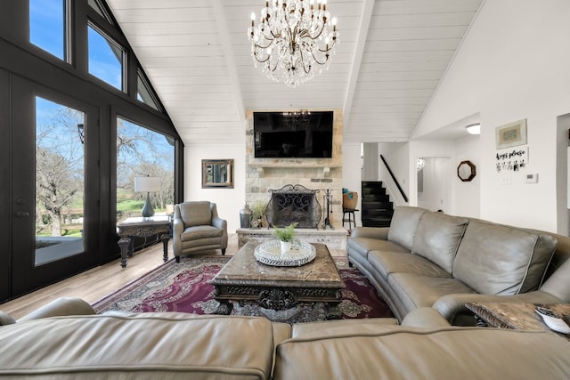 living room featuring high vaulted ceiling, hardwood / wood-style floors, a fireplace, and a chandelier