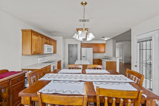 dining room featuring sink, a textured ceiling, a chandelier, and hardwood / wood-style flooring