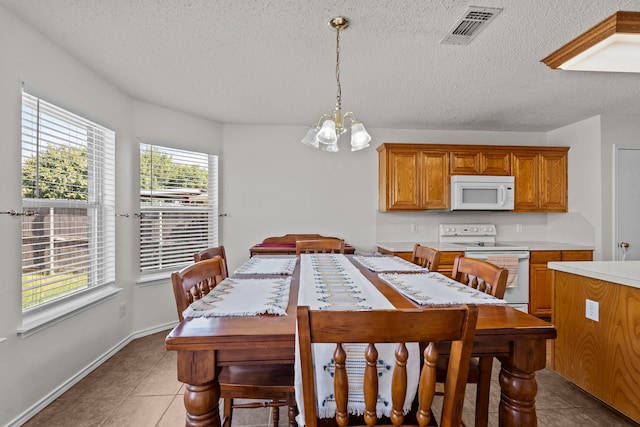 tiled dining room with a textured ceiling and a chandelier