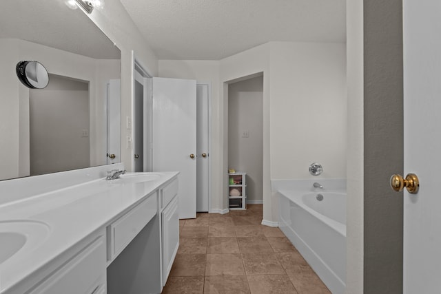 bathroom featuring tile patterned floors, a textured ceiling, double vanity, and a tub to relax in