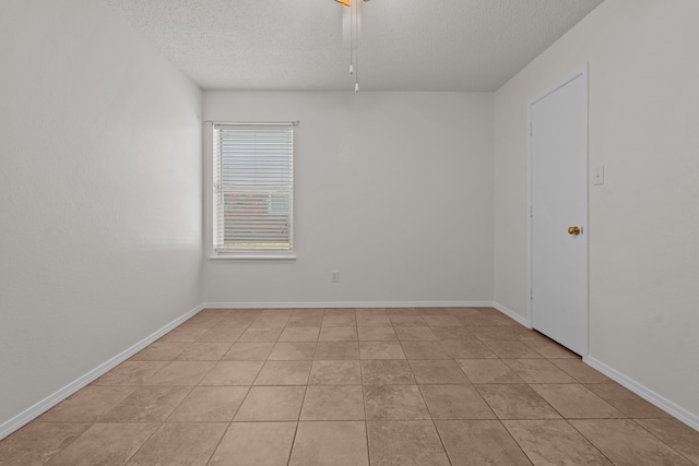 empty room with light tile patterned flooring and a textured ceiling