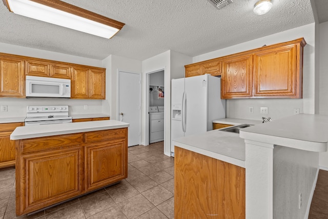 kitchen featuring a textured ceiling, white appliances, washer and clothes dryer, sink, and light tile patterned flooring