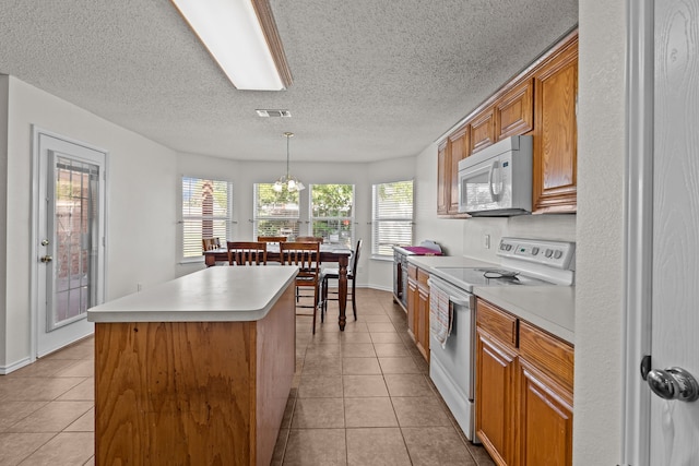 kitchen with light tile patterned flooring, pendant lighting, white appliances, and a center island