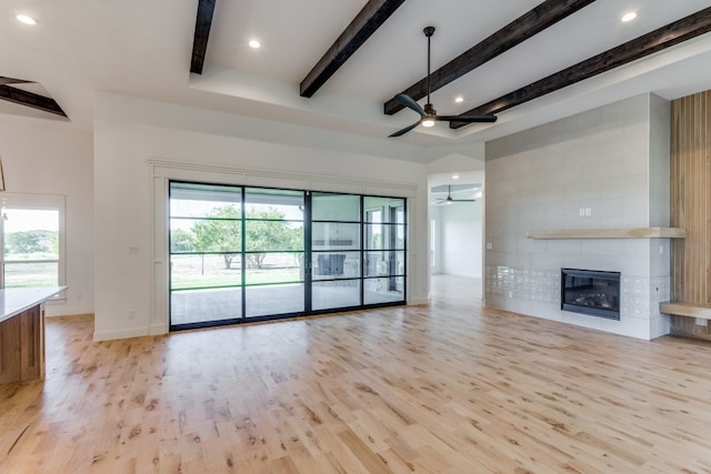 unfurnished living room featuring ceiling fan, plenty of natural light, light hardwood / wood-style floors, and a tile fireplace