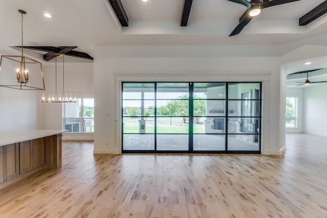 unfurnished living room with beamed ceiling, ceiling fan with notable chandelier, and light hardwood / wood-style flooring