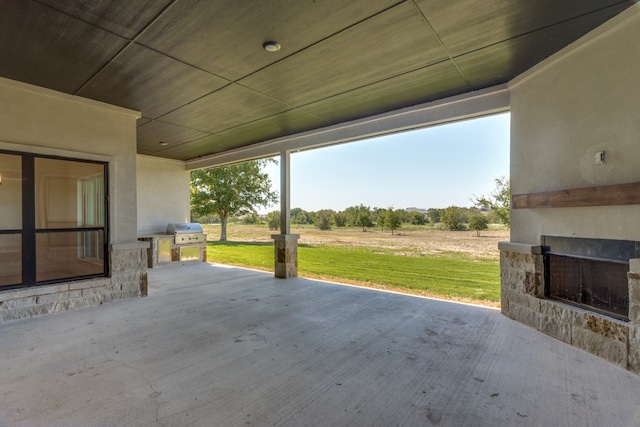 view of patio / terrace with a grill, an outdoor fireplace, and a rural view